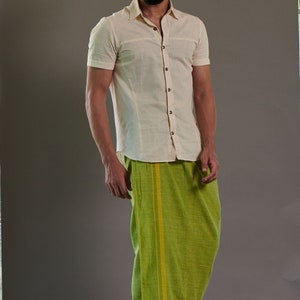 May include: A man wearing a light cream short-sleeved shirt and a green and yellow striped dhoti.