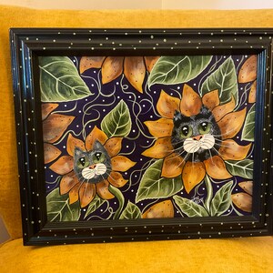 May include: Framed painting of two black cats with green eyes peeking out of sunflowers on a purple background with white dots.