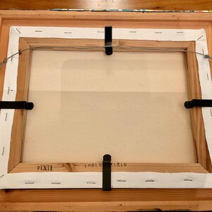 May include: The back of a framed canvas painting with a white canvas and a wooden frame. The frame has a white paper backing with staples and a wire attached to the top for hanging. The canvas is labeled with the numbers "1710", "1901", and "IXXI".