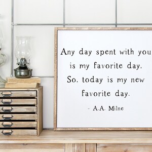 May include: A white framed sign with a black and white quote that reads "Any day spent with you is my favorite day. So, today is my new favorite day. - A.A. Milne".