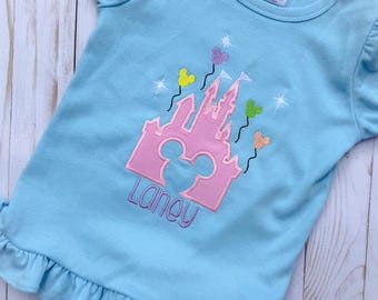 Puede incluir: Camiseta azul claro de manga corta con un diseño de castillo rosa, globos de Mickey Mouse y el nombre "Laney" bordado en morado. La camiseta tiene mangas con volantes y un dobladillo con volantes. Hecha de un material suave y cómodo.
