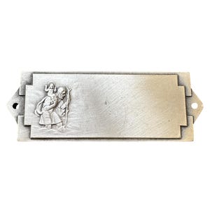 Könnte beinhalten: Eine silberfarbene Metallplakette mit einem Reliefbild des Heiligen Christophorus, der ein Kind trägt. Die Plakette hat einen leeren Platz zum Gravieren.