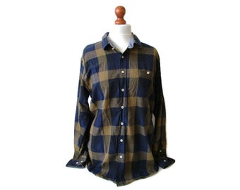 May include: A long-sleeved, button-down shirt in a classic plaid pattern. The shirt features a navy blue and tan color scheme, with a button-down front, a chest pocket, and buttoned cuffs. The shirt is displayed on a mannequin.