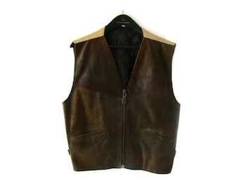 May include: A brown leather vest with a tan shoulder detail and a black interior. The vest has a V-neck, a full-length zipper, and two front pockets. It is hanging on a black hanger against a white background.