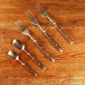May include: A set of five pieces of flatware consisting of three metal forks and two metal spoons. Each utensil features a brown handle secured with two small metal rivets, creating a uniform appearance across the entire cutlery collection.