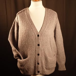 May include: A gray knitted cardigan with a v-neck, button closure, and two pockets.