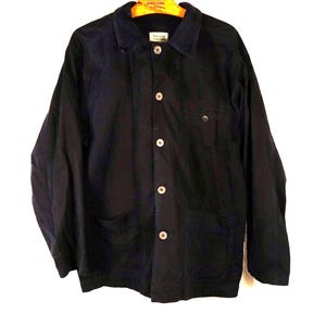 May include: A dark navy blue long-sleeve jacket featuring a classic collar, a front button-down closure with five light-colored buttons, two large patch pockets at the waist, and a single chest pocket. The garment is displayed on a wooden hanger.