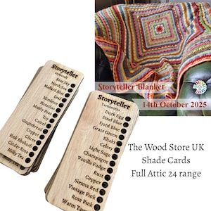 May include: A colorful, handmade Storyteller blanket with a square design, displayed on a green surface. Two wooden shade cards list yarn colors like Blue Sky, Khaki, and Sienna Red. Text on the cards reads "Storyteller" and "The Wood Store UK".