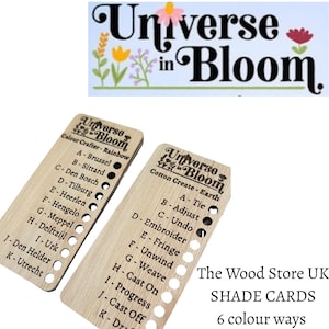 May include: Wooden shade cards from "Universe in Bloom" with text and color swatches. The cards list color names and crafting terms. The top of the image has the words "Universe in Bloom" with floral illustrations. The text "The Wood Store UK" is also visible.
