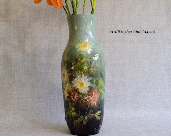 Puede incluir: Un jarrón de cerámica pintado a mano, de 34 cm de altura, con un diseño floral de flores blancas, amarillas y marrones. El jarrón tiene una base verde y oscura, con lirios naranjas.