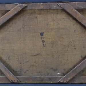 May include: The back of a wooden frame with a canvas stretched over it. The canvas is a light brown color and has some faint markings on it. The frame is made of dark wood and has a simple design.
