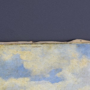 May include: Close-up of a painting with a blue and yellow sky. The painting is framed in a wooden frame.