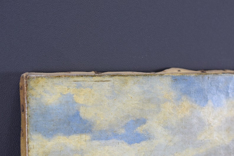May include: Close-up of a painting with a blue and yellow sky. The painting is framed in a wooden frame.
