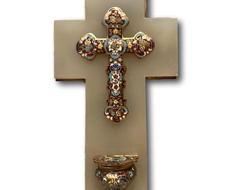 May include: A religious wall cross with a decorative, ornate cross at the center. The cross is embellished with gold, red, blue, and white enamel details. Below the cross is a small, matching container.