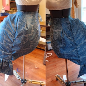 May include: A blue and white patterned fabric skirt with a ruffle at the bottom. The skirt is displayed on a mannequin on a stand.