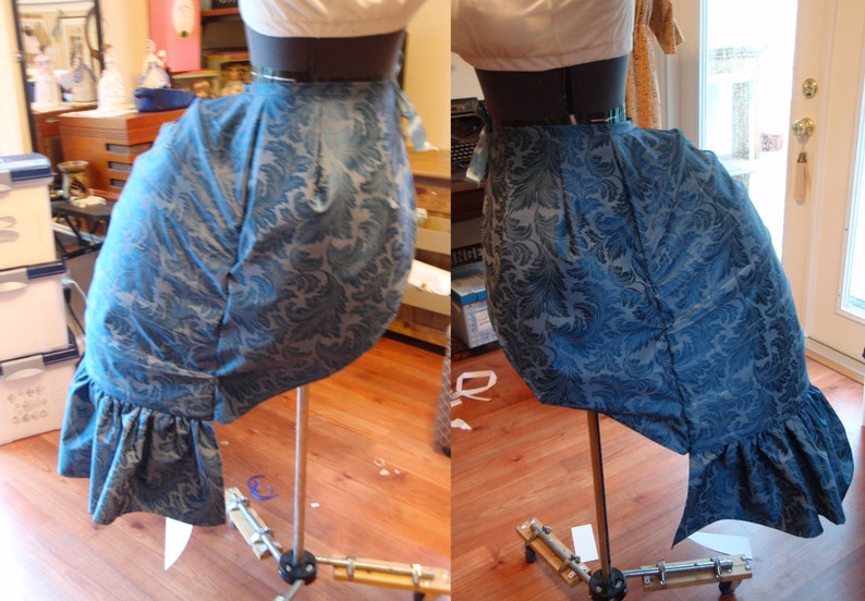 May include: A blue and white patterned fabric skirt with a ruffle at the bottom. The skirt is displayed on a mannequin on a stand.
