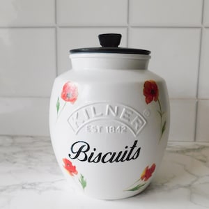 May include: White ceramic biscuit jar with a black lid and poppy flower illustrations. The jar features the embossed "Kilner Est 1842" logo and the word "Biscuits" in a black script font.