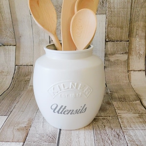 May include: White ceramic utensil holder with the text "Kilner Est 1842 Utensils" on the front. The holder is filled with wooden spoons and spatulas.