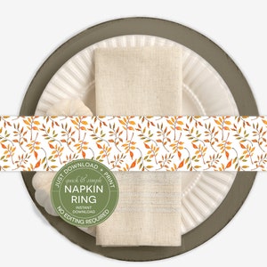 May include: Printable napkin ring design featuring a pattern of orange and green leaves on a white background. The text "Just Download & Print quick & simple Napkin Ring Instant Download No Editing Required" is on a green circle.