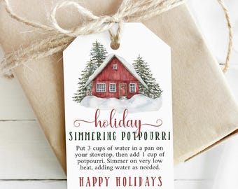 May include: A white gift tag with a watercolor illustration of a red cabin in a snowy forest. The tag has the text "holiday simmering potpourri" and instructions for making a simmering potpourri. The text also says "Happy Holidays" and "From: Everley & Wilson".