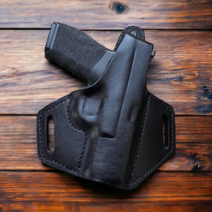 May include: A black leather holster for a handgun. The holster has a belt loop and a snap closure.