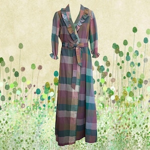 May include: A long, plaid dress in shades of purple, green, and brown. The dress features a V-neck with ruffled trim, long sleeves with ruffled cuffs, and a matching belt. The dress is a vintage style.
