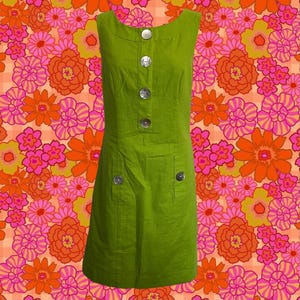 May include: A sleeveless green linen dress with a button-up front and two pockets. The dress has a simple, classic design.