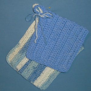 May include: Two handmade crochet potholders in shades of blue and white. One is solid light blue with a loop and tie, the other has stripes of light blue, medium blue, and white. A yellow pin is attached to the light blue potholder.