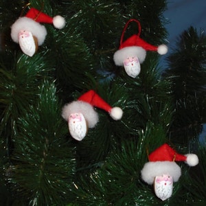 May include: A Christmas tree decorated with handmade Santa Claus ornaments. The ornaments are made from felt and have white faces with pink cheeks and black eyes. The ornaments are hanging from the branches of the tree.