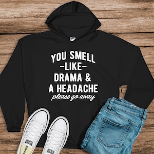 May include: Black hooded sweatshirt with the text "You smell -like- drama & a headache please go away" in white.