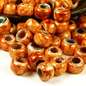 May include: A pile of orange ceramic beads with a speckled brown glaze. The beads have a silver-colored metal ring through the center of each bead.