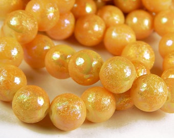 May include: A strand of iridescent orange glass beads. The beads have a textured surface and are strung on a clear thread.