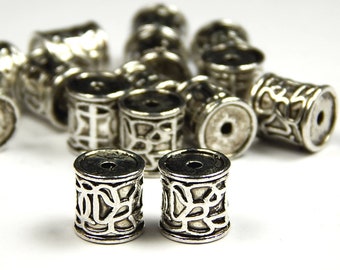 May include: A group of silver metal beads with an intricate Celtic knot design. The beads are cylindrical and have a hole in the center for threading.