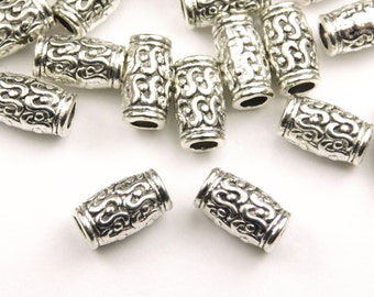 May include: A group of silver metal beads with an ornate design. The beads are cylindrical and have a smooth, polished finish.