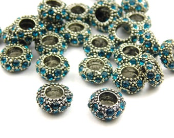 May include: A group of silver-toned spacer beads with a turquoise blue rhinestone design. The beads are round and have a hole in the center for stringing.