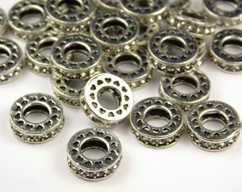 May include: Silver-toned metal spacer beads with a heart-shaped design and clear rhinestones. The beads are perfect for adding a touch of sparkle to jewelry projects.