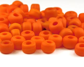 May include: A pile of bright orange round beads with a hole in the center. The beads are made of glass and have a smooth, glossy finish.