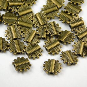 May include: A group of antique gold metal beads with a circular design and a raised center. The beads have a textured surface and are perfect for jewelry making.