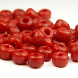May include: A pile of bright red round beads with a hole in the center. The beads are made of a smooth, glossy material.