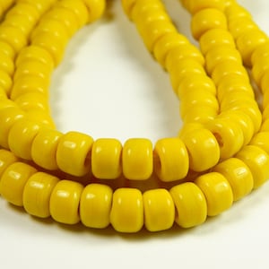 May include: A strand of bright yellow plastic beads. The beads are round and have a hole in the center. The beads are strung together on a clear string.
