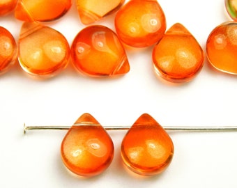 Op de afbeelding: Een close-up van twee oranje glazen traanvormige kralen op een zilveren draad. De kralen zijn doorschijnend en hebben een lichte glans.
