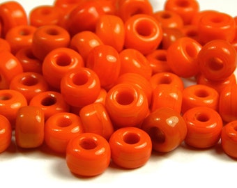 May include: A collection of vibrant orange, donut-shaped beads. These beads have a glossy finish and a hole running through the center, perfect for jewelry making or crafting projects. The beads are uniform in size and shape.