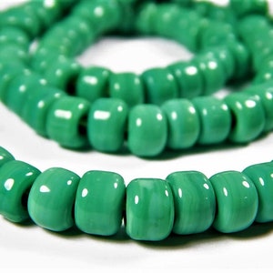 May include: A strand of green glass beads, each bead is round and has a slightly irregular shape.