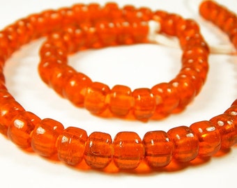 May include: A strand of orange glass beads. The beads are round and have a slightly textured surface.