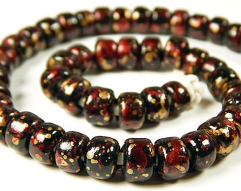 May include: A strand of black beads with red and gold speckles. The beads are round and have a glossy finish.