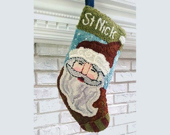 May include: A green and blue Christmas stocking with a Santa Claus design and the name "St. Nick" embroidered on the front.