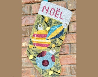 May include: A green and yellow Christmas stocking with the word "NOËL" embroidered on the cuff. The stocking is decorated with two ornaments, one red and yellow and the other blue and red, and a string of yellow lights.