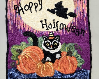 May include: A purple and black rug with a black cat wearing a witch's hat sitting on top of pumpkins. The rug has the words "Happy Halloween" on it.