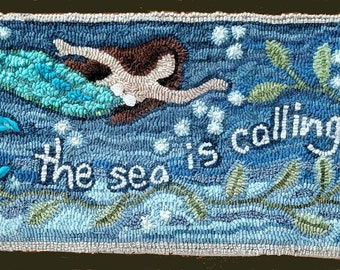 May include: A blue and green mermaid with brown hair swims in a blue ocean with white bubbles. The text "The sea is calling" is written in white on the blue background.