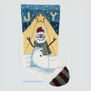 May include: A Christmas stocking with a snowman standing in front of a yellow star with the word "JOY" above the snowman.